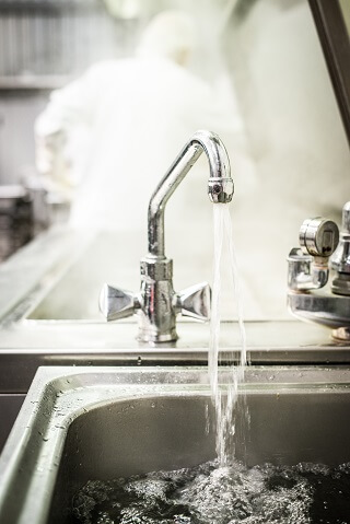 Warmes, strömendes Kranwasser in der Küche zum Auswaschen von Seitan